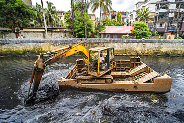 Municipality worker digging out garbage from a polluted canal using an excavator, in Guwahati, India on 27 May 2025.