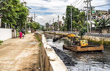 Municipality worker digging out garbage from a polluted canal using an excavator, in Guwahati, India on 27 May 2025.