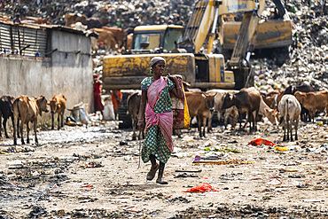 A woman ragpicker walks after collect reusable items at a garbage dumping site on May 27, 2025 in Guwahati, India.