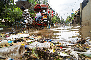 Residents commutes in a cycle rickshaw through a flooded street next to floating garbages after heavy monsoon rains in Guwahati, India on May 31, 2025.