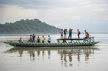 Passengers travel in a boat in the Brahmaputra river, in Assam, India