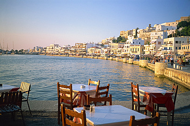 Tables and chairs in cafe on the harbour with the waterfront in the background, on Naxos, Cyclades Islands, Greek Islands, Greece, Europe