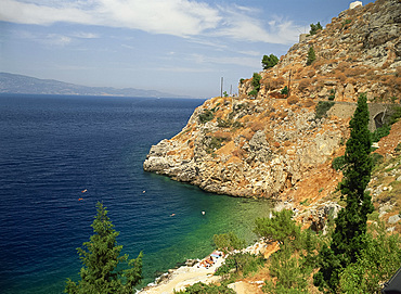 Swimmers in sea below cliffs on Hydra, Argo Saronic Islands, Greek Islands, Greece, Europe