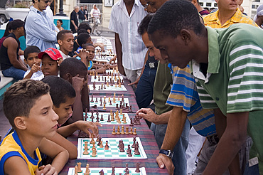 A group of school children competing in chess matches against adults, Parque Cespedes, Santiago de Cuba, Cuba, West Indies, Central America