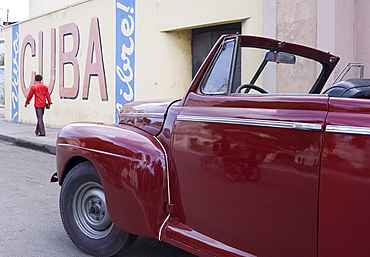 A vintage car near a 'Viva Cuba' sign painted on a wall in cental Havana, Cuba, West Indies, Central America