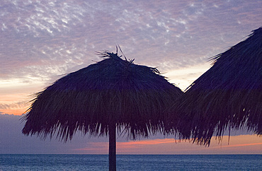 Thatched beach umbrellas in silhouette at sunset, Playa Ancon, Trinidad, Cuba, West Indies, Central America