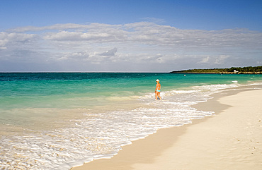 A woman walking in the surf at Playa Esmeralda, Carretera Guardalavarca, Cuba, West Indies, Central America