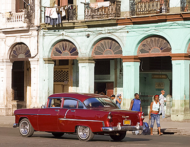 A vintage 1950's American Chevrolet passing an arcade in Paseo de Marti, Central Havana, Cuba, West Indies, Central America