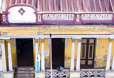 A man leaning out from a porch on an old building in Santiago de Cuba, Cuba, West Indies, Central America