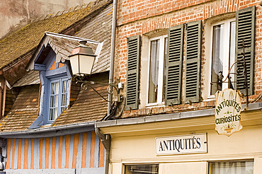 Half timbered house painted pink and blue and signs in Beaumont en Auge, Pays d'Auge, Normandy, France, Europe