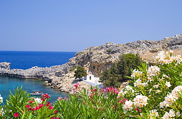 A small white church and fising boat in St. Paul's Bay near Lindos, Rhodes, Dodecanese Islands, Greek Islands, Greece, Europe