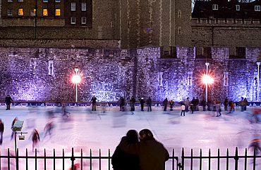 Couple watching skaters on the ice rink next to The Tower of London, London, United Kingdom, Europe