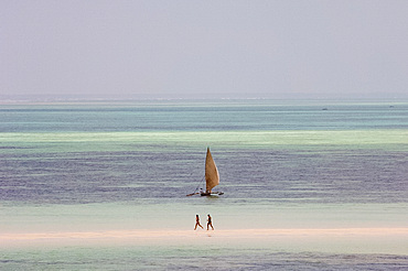 People walking on sandbar and a sailing dhow in the Indian Ocean, Kiwendwa Beach, Zanzibar, Tanzania, East Africa, Africa