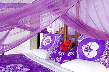 Purple mosquito netting and hibiscus flowers on a bed at the Shooting Star Hotel, Kiwendwa, Zanzibar, Tanzania, East Africa, Africa