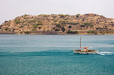 A small boat passing the island of Spina Longa, Crete, Greece, Europe