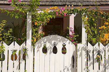 A white picket fence with pineapple shaped cutouts in front of a traditional cottage, Dunmore Town, Harbour Island, The Bahamas, West Indies, Central America