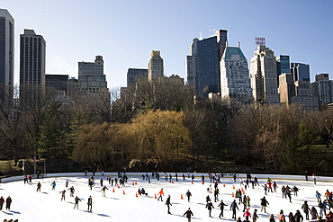 Skaters on the Woolman Rink in Central Park with the skyline behind, New York City, New York State, United States of America, North America