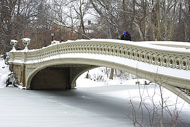 People walking across the Bow Bridge in Central Park after a snowstorm, New York City, New York State, United States of America