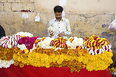 A man selling garlands of flowers outside a temple in Jaipur, Rajasthan, India, Asia