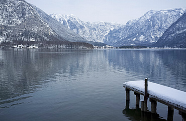 A snow covered dock and surrounding mountains on Halstatter See, Austria, Europe