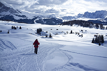 A woman walking on a snowy hiking trail in the Alpe di Siusi Ski resort near the town of Otisei in the Dolomites, South Tyrol, Italy, Europe