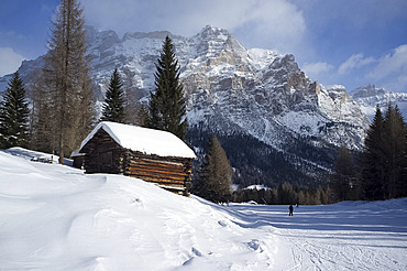 A snow covered wooden barn at the Alta Badia ski resort with Lavarella and Contourines mountains, Corvara, The Dolomites, South Tyrol, Italy, Europe