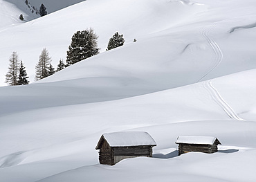 Two old wooden barns surrounded by deep snow in the Dolomites, South Tyrol, Italy, Europe