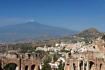 A view of Taormina from the Greek Theatre and Mount Etna smoking in the background, Taormina, Sicily, Italy, Europe