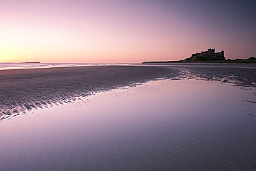 Bamburgh Castle and the beach at dawn in Bamburgh, Northumberland, England, United Kingdom, Europe