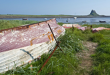 Old boats across the bay from Lindisfarne Castle on Holy Island, Northumberland, UK