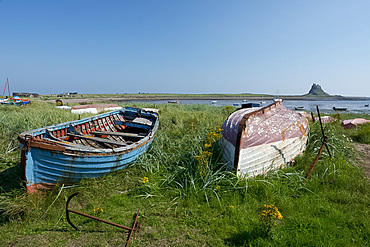 Old boats across the bay from Lindisfarne Castle on Holy Island, Northumberland, UK