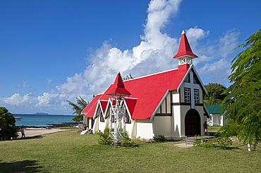 A newly wed couple posing for photos outside the red roofed church at Cap Malheureux on the northwest coast of Mauritius, Indian Ocean, Africa