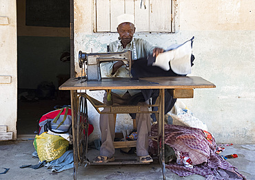 A local man making clothing with an old Singer Sewing Machine in Pangani, Tanzania, East Africa, Africa