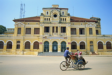 A cyclo passing the Old Post Office in Phnom Penh in Cambodia, Indochina, Southeast Asia, Asia