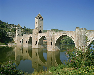 Reflections of the bridge and towers of the Pont Valentre across the River Lot at Cahors, in the Dordogne Lot Valley, Midi Pyrenees, France, Europe