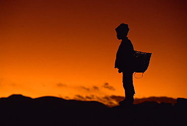 Young boy silhouetted against sky at dusk, Tibet, China, Asia