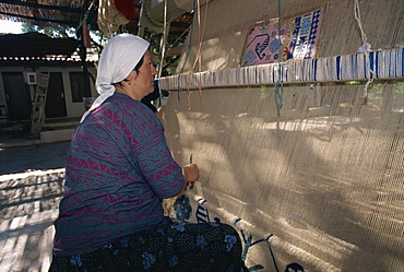 Woman weaving wool carpet on a loom in a workshop at Kusadasi, Anatolia, Turkey, Asia Minor, Eurasia