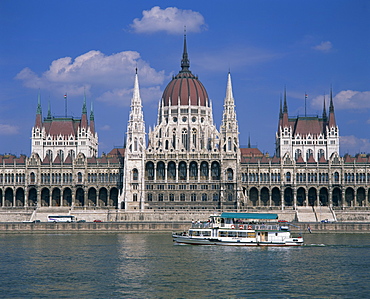 Tourists on a boat on the River Danube pass the Parliament Building in Budapest, Hungary, Europe