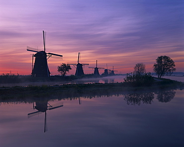 Reflections of a line of windmills in a misty landscape at Kinderdjik, UNESCO World Heritage Site, Holland, Europe