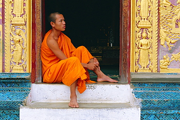 Monk sitting in temple doorway, Wat Xieng Thong, Luang Prabang, Laos