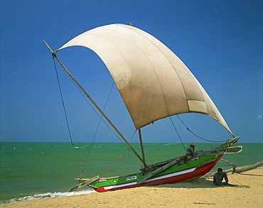 Fishermen in the shade of a sail on a fishing boat on the beach at Negombo, Sri Lanka, Asia