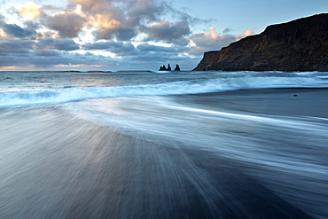 Looking towards the sea stacks of Reynisdrangar at sunrise from the black volcanic sand beach at Vik i Myrdal, South Iceland, Polar Regions