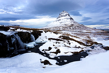 Kirkjufell (Church Mountain) covered in snow with a frozen river and waterfall in the foreground, near Grundarfjordur, Snaefellsnes Peninsula, Iceland, Polar Regions