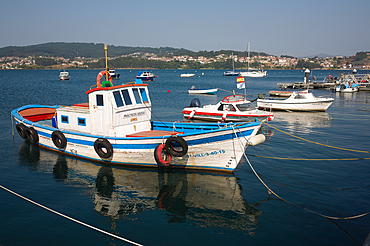 Boats including a colourful fishing vessel in the harbour of Combarro Galicia Spain