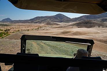 View over Hoarusib Riverbed from inside a safari vehicle, mountain range in background, Puros, north of Sesfontein, Nambia, Africa