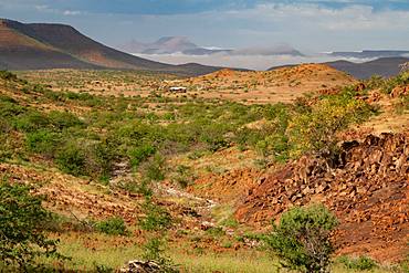 Colourful rocky landscape high up in the hills, with mountain camp in the background, Etendeka, Namibia, Africa