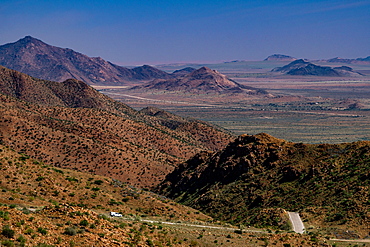 Aerial view of a car going down the winding road to barren plains, from the top of Spreethoogte Pass, Namib-Naukluft, Namibia, Africa