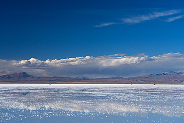 The beauty of the salt flats reflecting the clouds and mountains after rainfall, three 4WD vehicles in the distance, Uyuni, Bolivia, South America