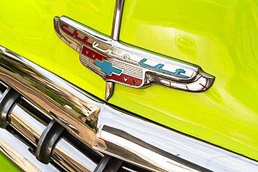 Bonnet insignia and bumper detail from green Chevrolet classic car, Havana, Cuba