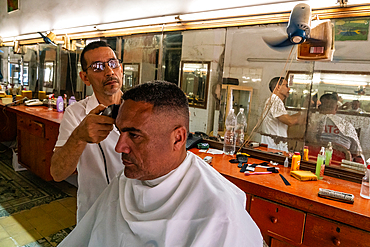 Cuban having his haircut, Old Havana, Cuba (Model Release of customer)